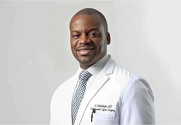 Smiling doctor in medical coat against light background.