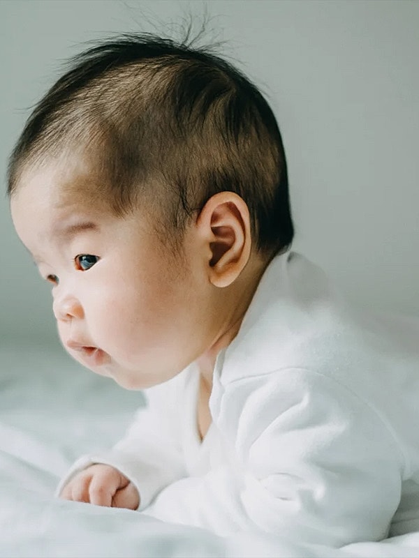 Baby peacefully exploring on a soft surface.