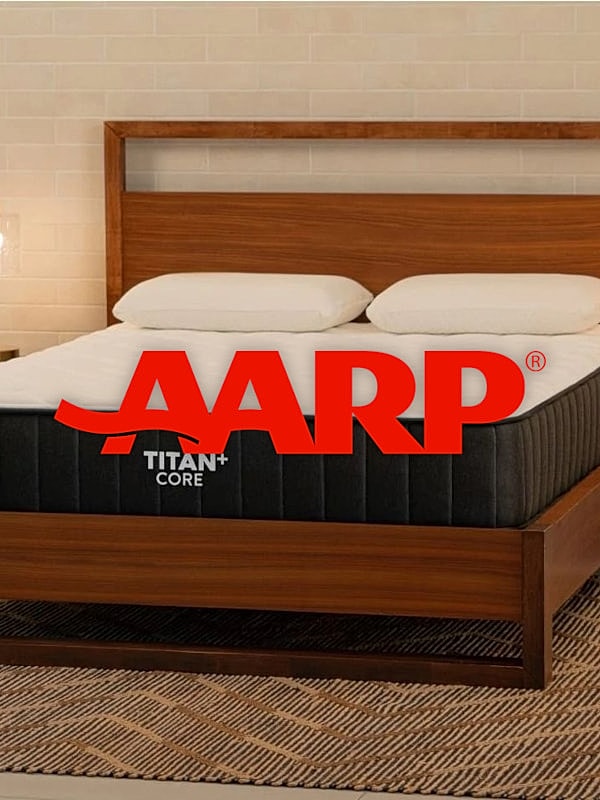 AARP branded mattress with pillows on wooden bed.