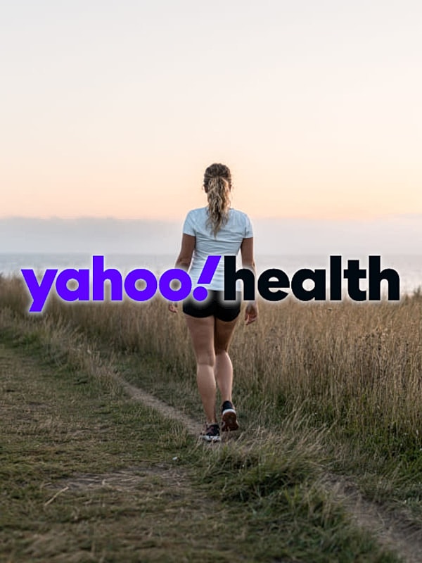 Woman walking on a path at sunset.