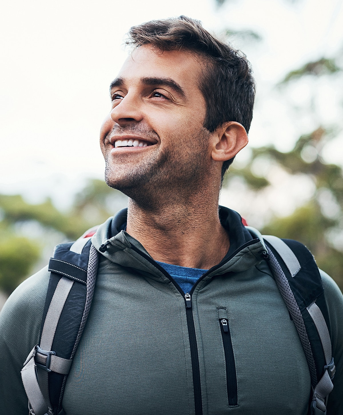 Smiling degenerative disc disease with backpack in outdoor setting.