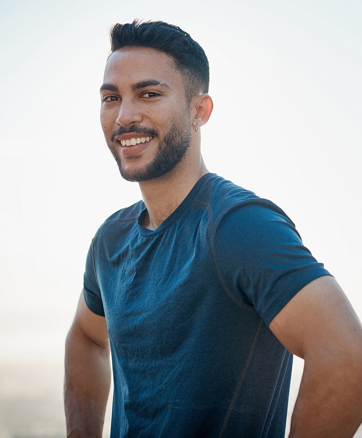 Smiling spine tumor treatment patient model in a blue shirt outdoors.