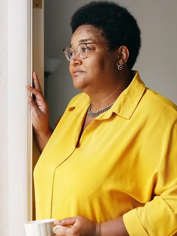 Woman in a yellow shirt holding a cup.