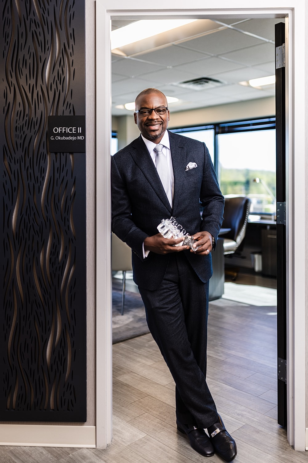 Professional man holding award in office doorway.