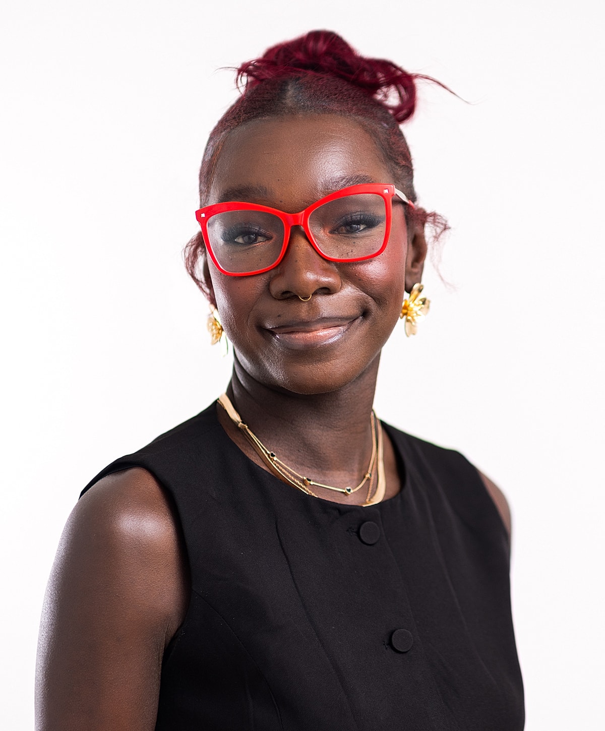 Smiling woman with red glasses and elegant jewelry.