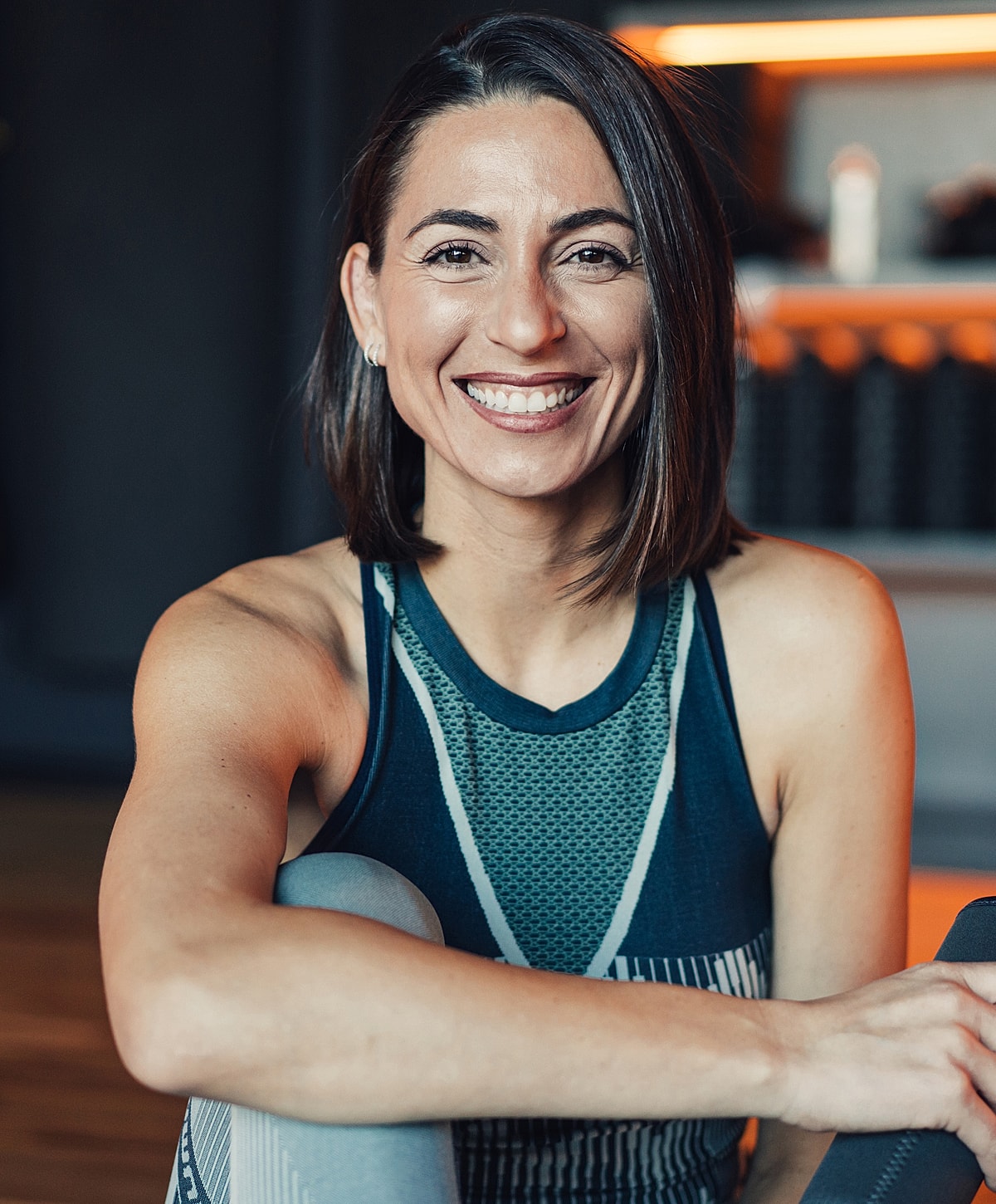 Smiling laser spine surgery patient model in activewear, sitting indoors.