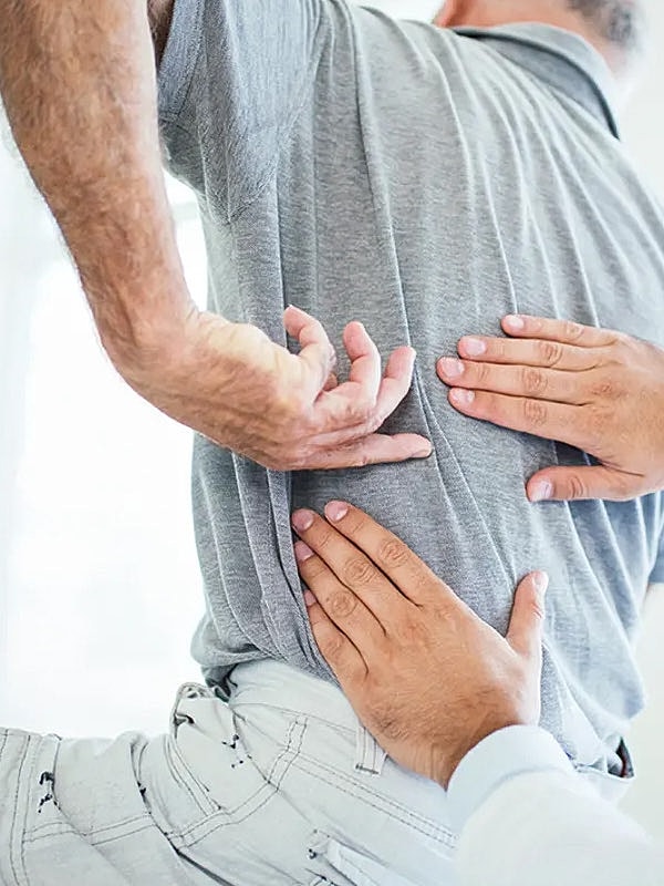 Hands applying pressure to a person's back.