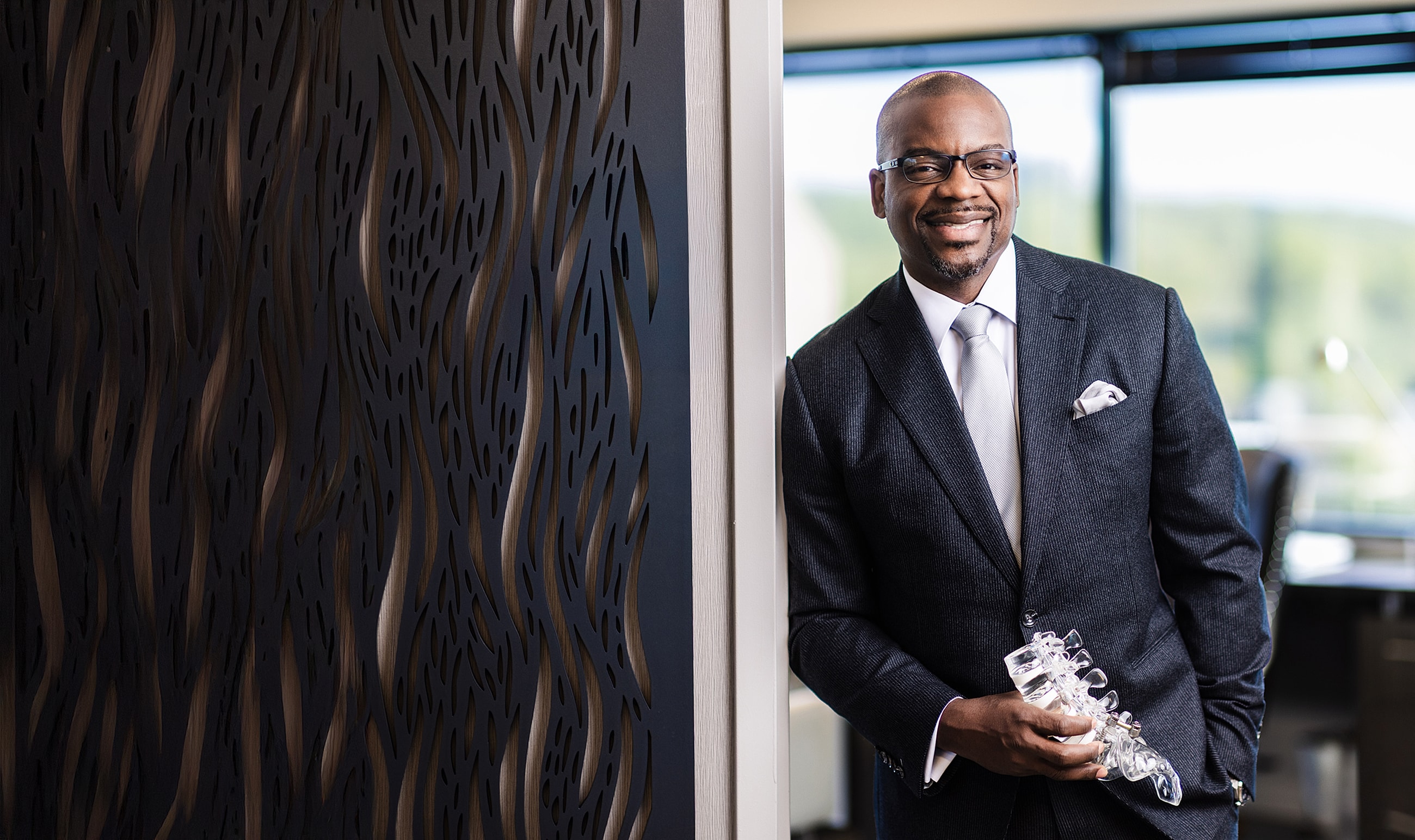 Smiling man in a suit holding a glass object.