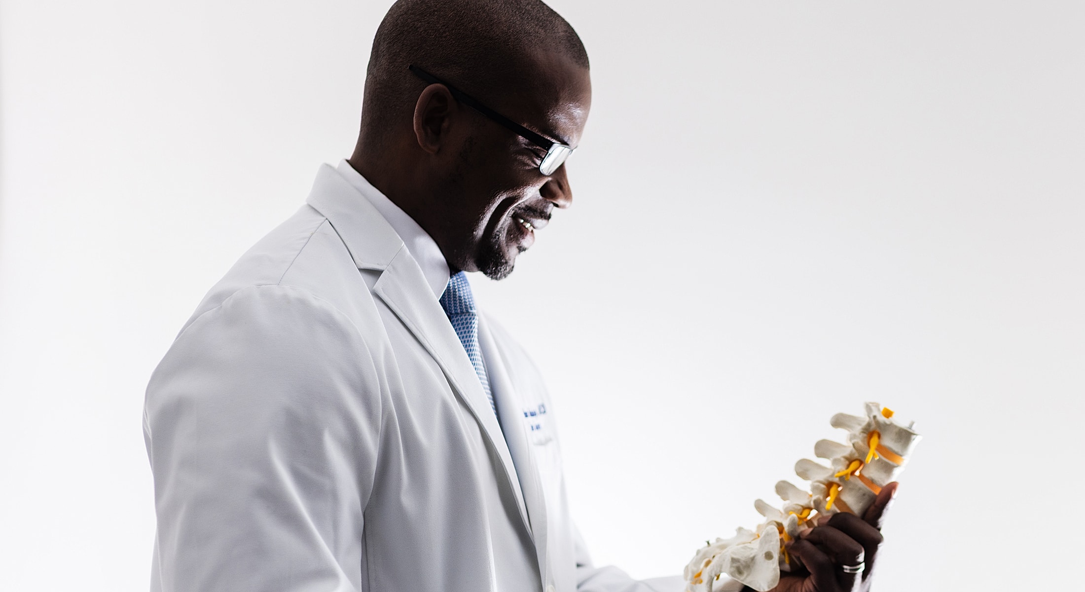 Doctor examining a spinal model with a smile.