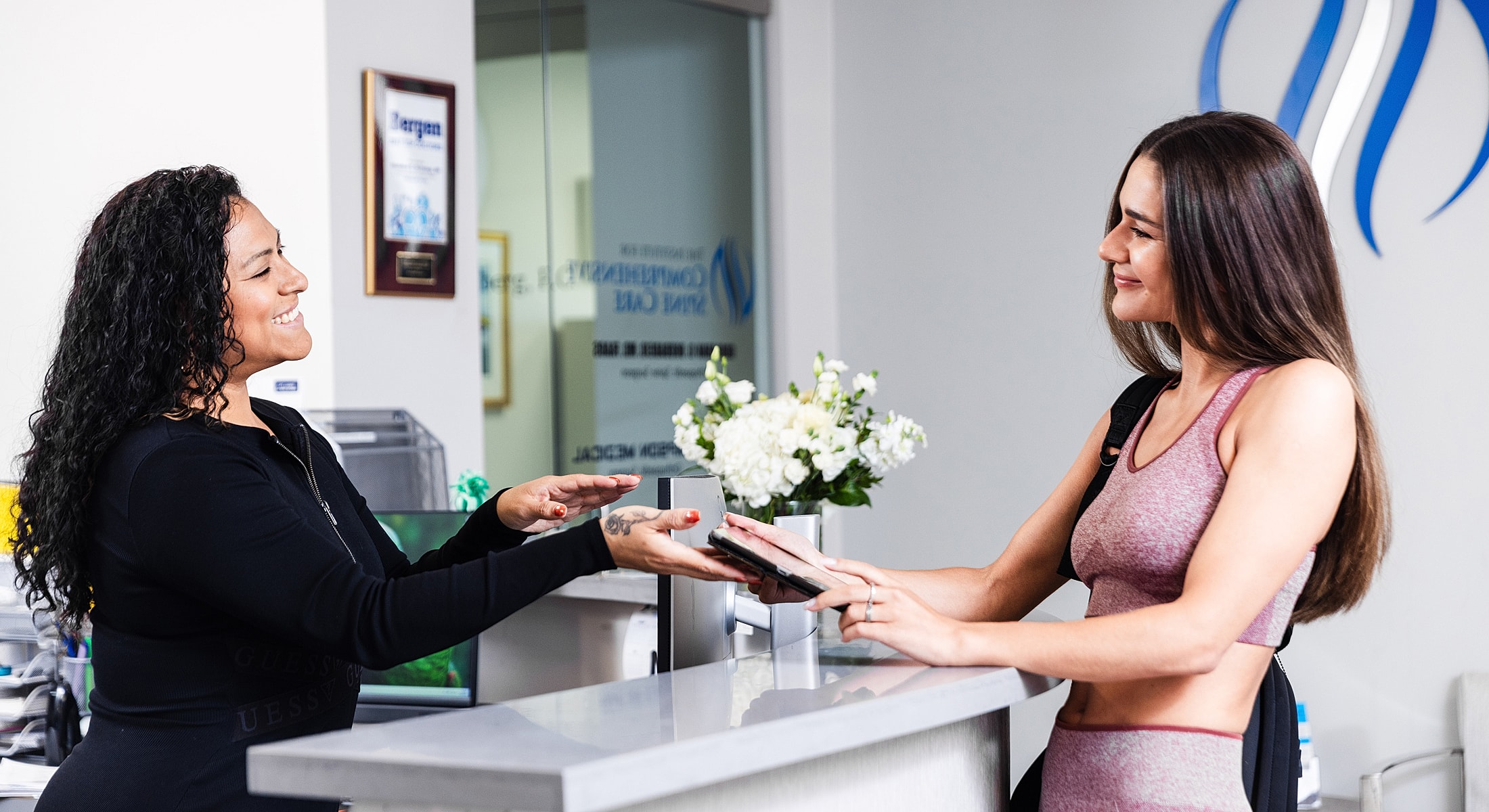 Receptionist assisting a client at a front desk.